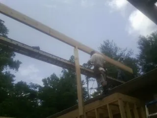 Carpenter setting a ridge beam over a new addition frame — Ice Dam Removal by Roofing Brothers in Ivydale