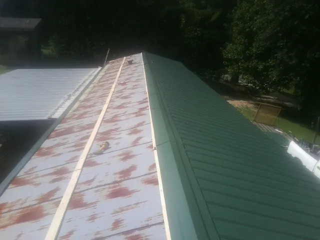 Old rusted panels beside newly installed green metal roofing — Wind Damage Roof Repair by Roofing Brothers in Ivydale