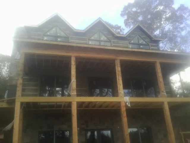 Dormers and porch framing on a large log home under construction — Roof Coating work by our crew in Ivydale