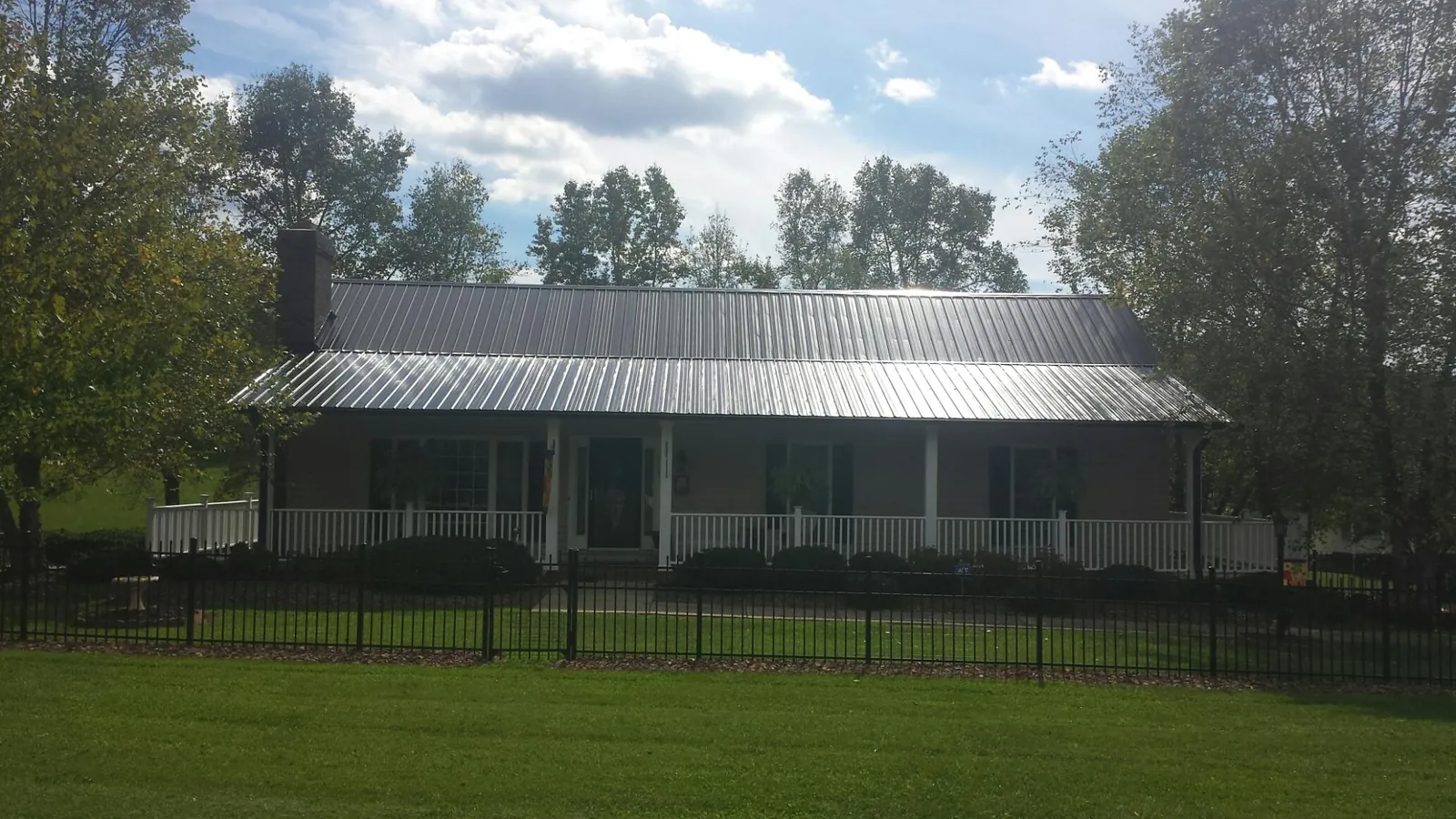 Gray metal roof on a brick ranch with a full width front porch — Gutter Guard Installation work by our crew in Ivydale