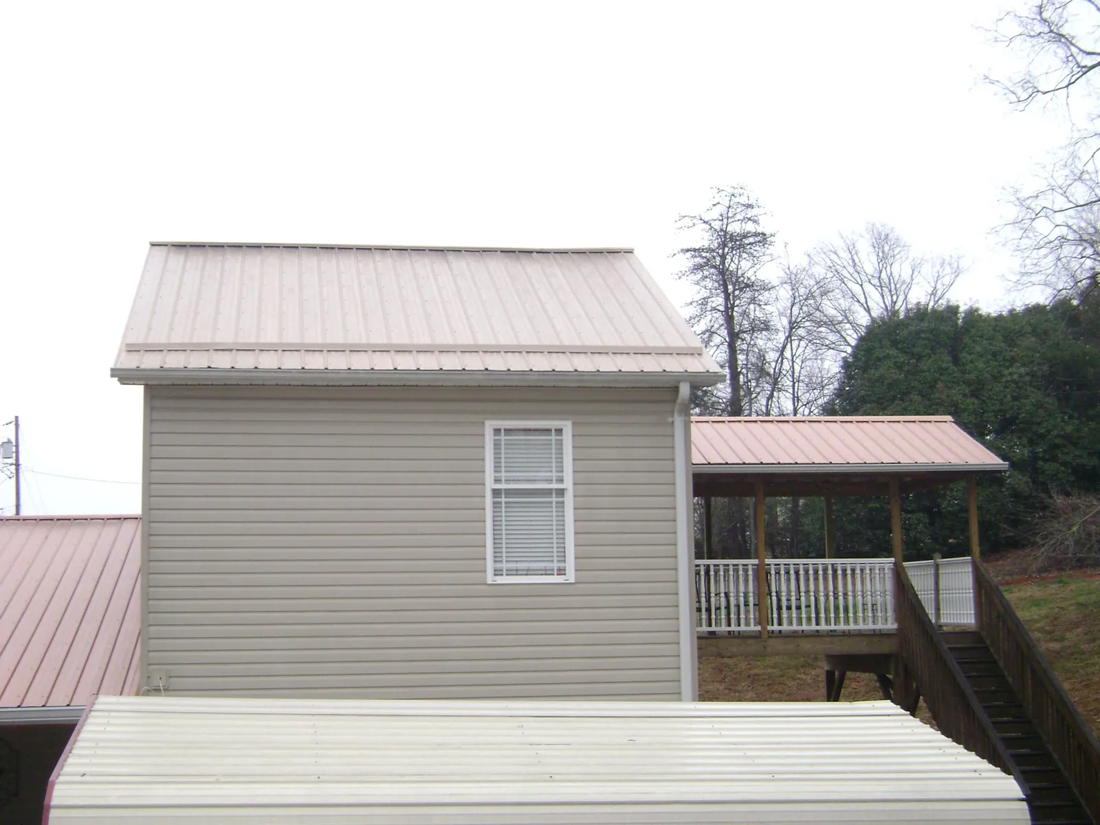 Tan metal roofs on a two story addition and attached porch, from a Roof Replacement job in Ivydale