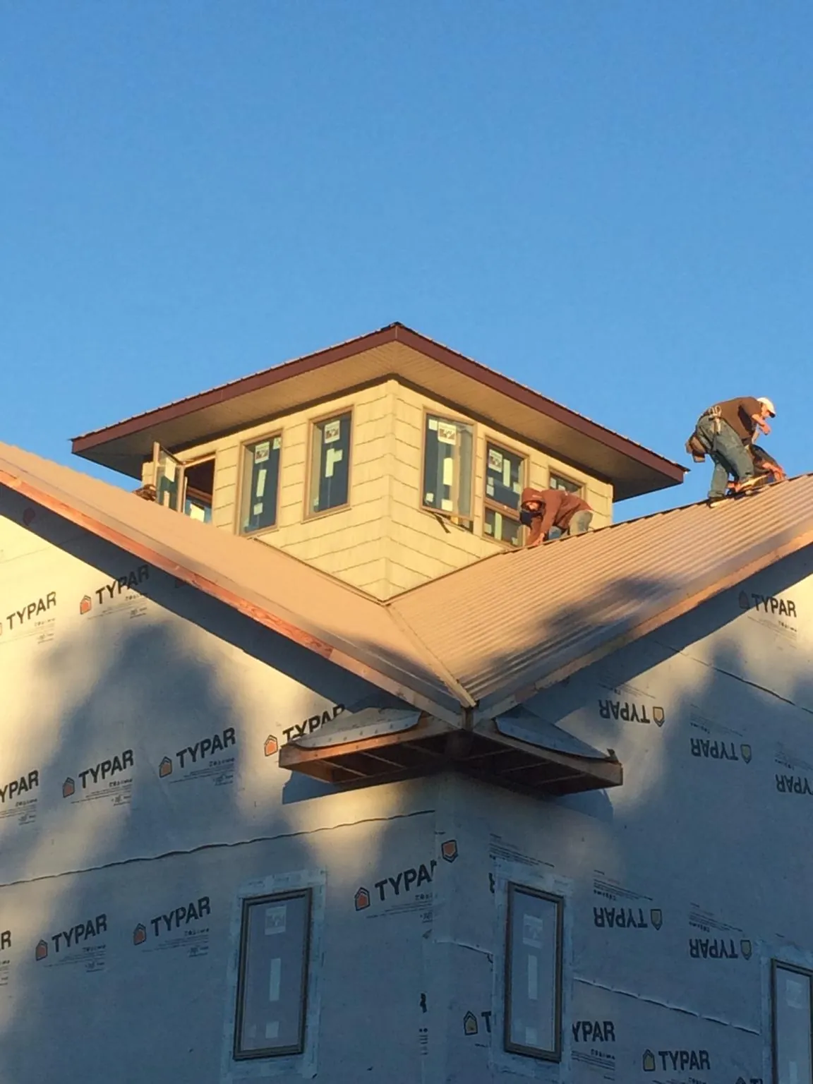 Roofers working around a rooftop cupola on a new metal roof at sunset — Roof Waterproofing in Ivydale by Roofing Brothers